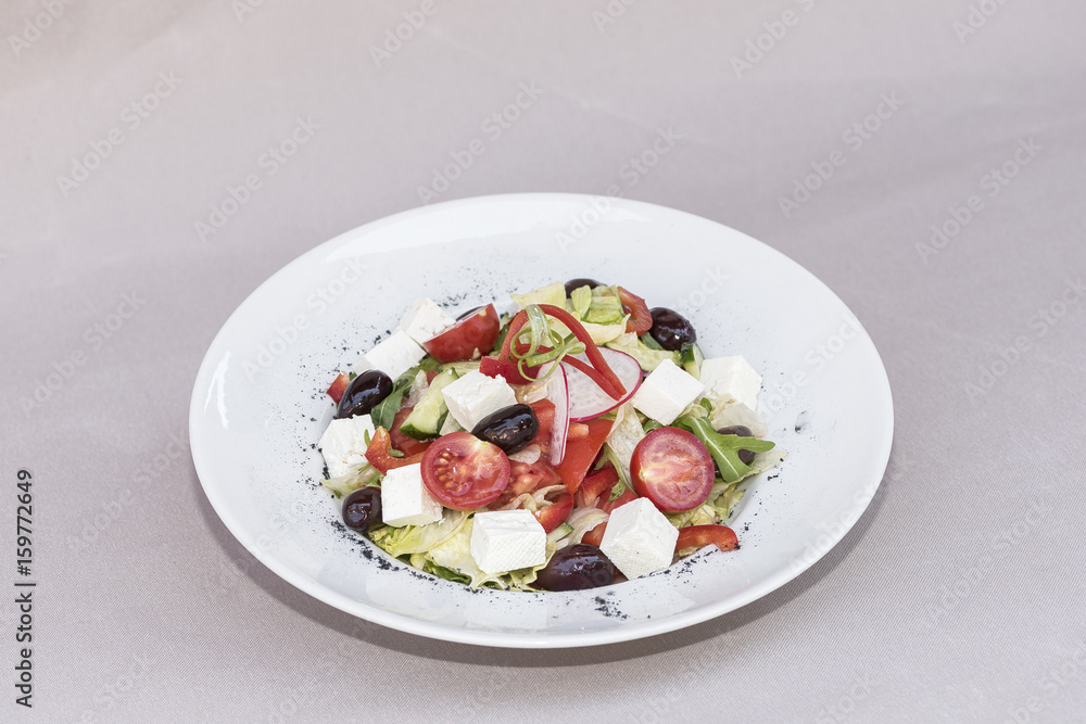 Fresh greek salad, decorated with herbs, isolated on light background, white plate Fresh greek salad, decorated with herbs, isolated on light background, white plate
