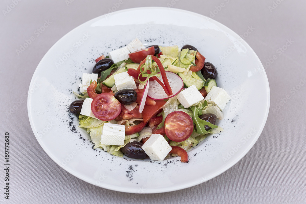 Fresh greek salad, decorated with herbs, isolated on light background, white plate