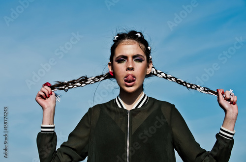 woman with long braids in hands showing sexy tongue