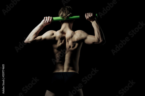 Fototapeta Naklejka Na Ścianę i Meble -  Athletic man with fit back holding baseball bat in arms