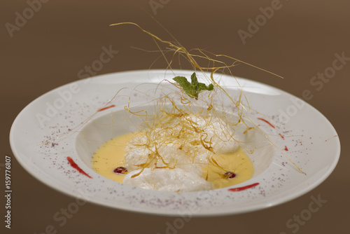Floating Island, a European dessert of French origin called Oeufs a la neige in French, in Hungarian Madartej (Bird's Milk), white plate, brown background