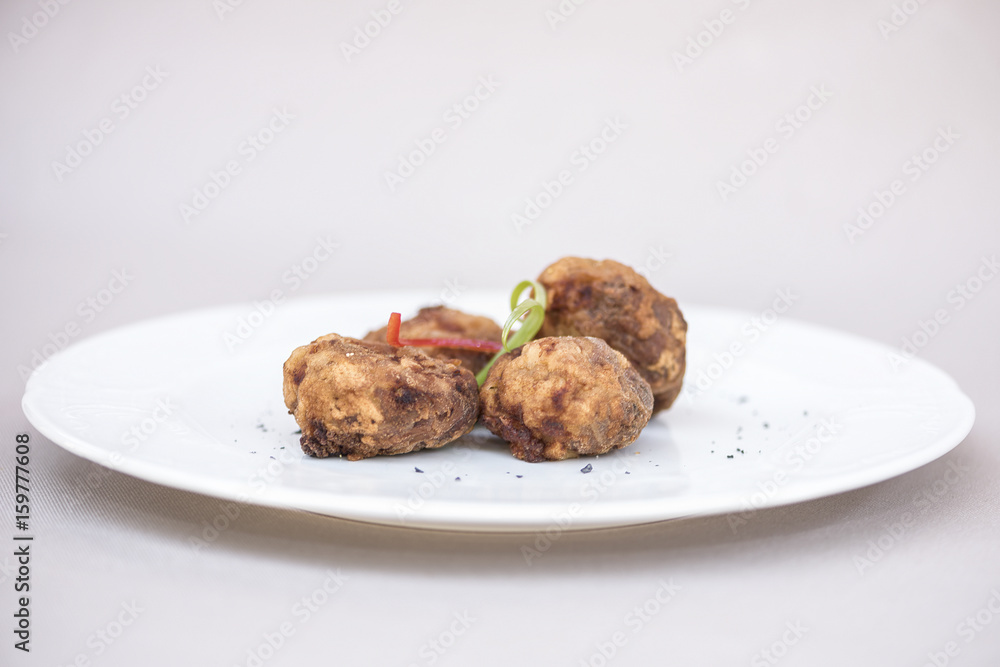 Fried pane sweetbreads, decorated with herbs, isolated on light background, white plate Fried pane sweetbreads, decorated with herbs, isolated on light background, white plate