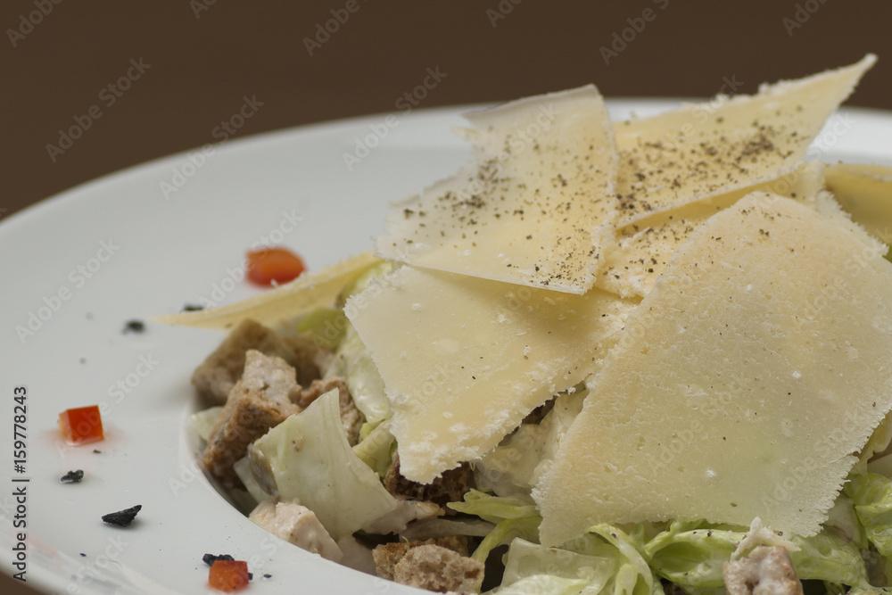 Grilled meat salad, served with parmesan and rucola, isolated on light background, white plate