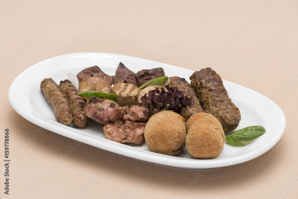 Traditional Romanian food plateau, with sausages, grilled meat, sweetbreads, potatoes, pickles, mustard, polenta, mushrooms, mici and vegetable salad, decorated with herbs, isolated on light backgroun