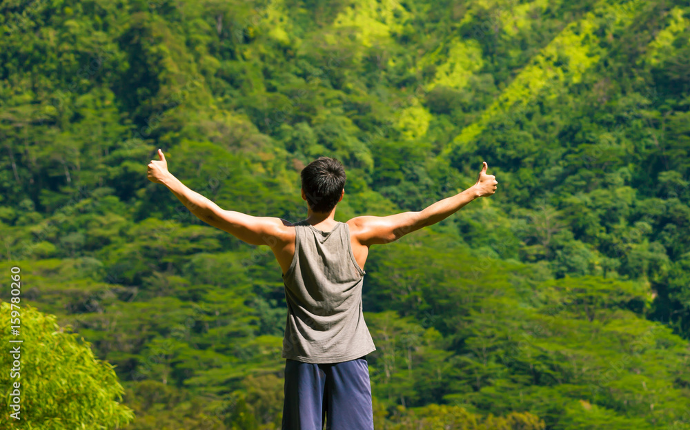 Young man standing on a mountain with thumbs up in the air. Healthy active lifestyle and fitness concept. Young man standing on a mountain with thumbs up in the air. Healthy active lifestyle and fitness concept.
