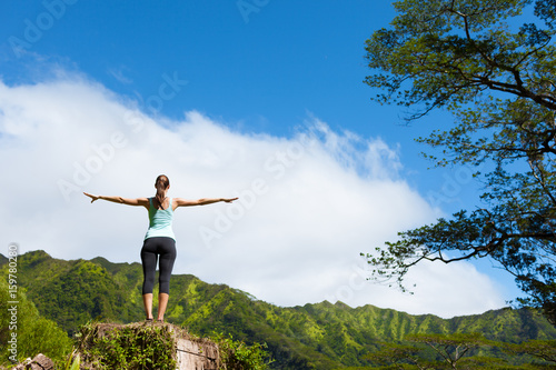 Woman standing up on a mountain feeling free with her arms in the air.