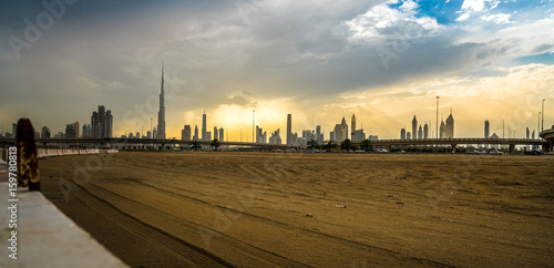 Photography Panoramic view of business bay, downtown area of Dubai and two arab men take a walk on the promenade at cloudy day