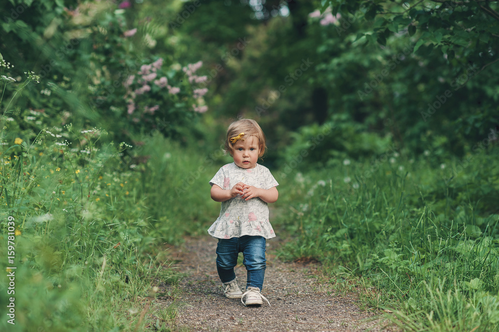 the forest footpath, the little girl walks on a path among green trees of the park the forest footpath, the little girl walks on a path among green trees of the park