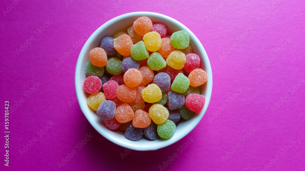 Sweet jujubes in white pot on pink background top view Sweet jujubes in white pot on pink background top view