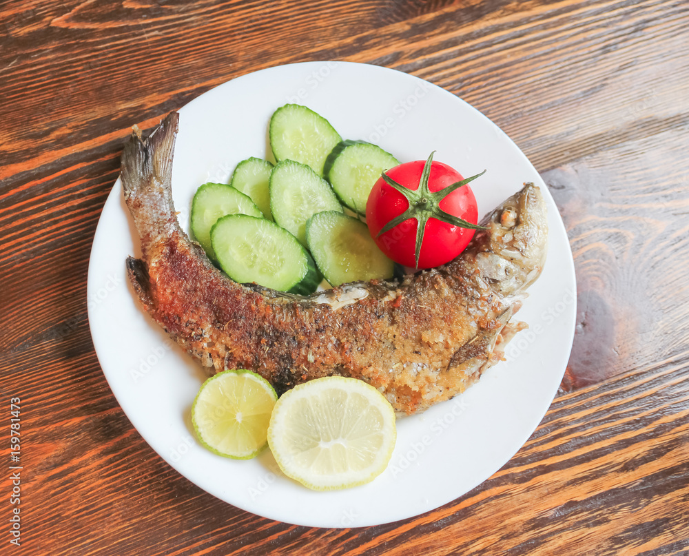 Fried fish with vegetables. wild grayling fried in breadcrumbs, with a Golden crust.. Fried fish with vegetables. wild grayling fried in breadcrumbs, with a Golden crust..