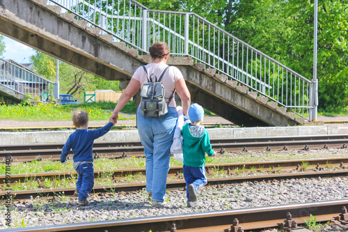 06.06.2017 Russia, Strugi-Krasnyye. A woman with two kids crossing the railroad across the tracks, over the tracks. Caution, danger, crossing in the wrong place..editorial