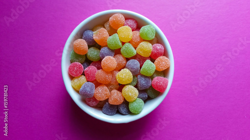 Sweet jujubes in white pot on pink background top view