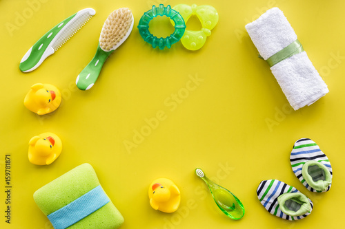 Baby care with bath set, ducklings and towel on yellow background top view mockup