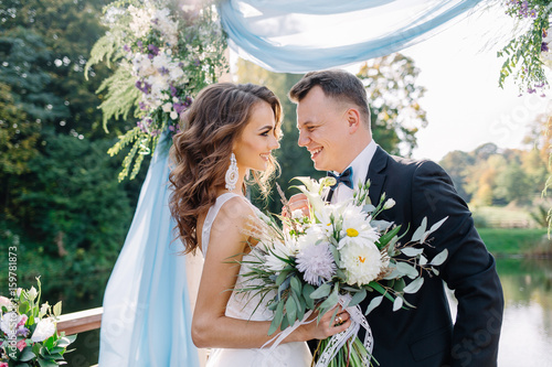 A happy groom looks into the eyes of his beautiful bride in the nature