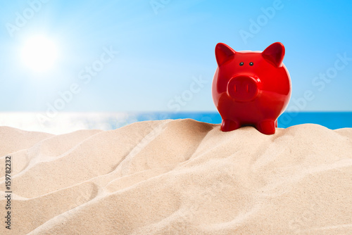 On the Beach - piggy bank on a sand dune in front of beautiful azure sea on a sunny day © trendobjects