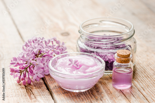 spa cosmetic set with lilac flowers wooden desk background © 9dreamstudio