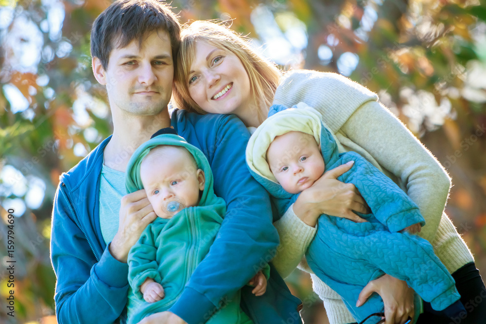 outdoor portrait of young happy smiling mother and father with twin babies on natural background outdoor portrait of young happy smiling mother and father with twin babies on natural background