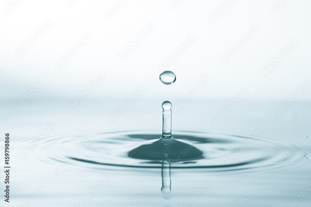 Water drop and splash on water surface on blue background