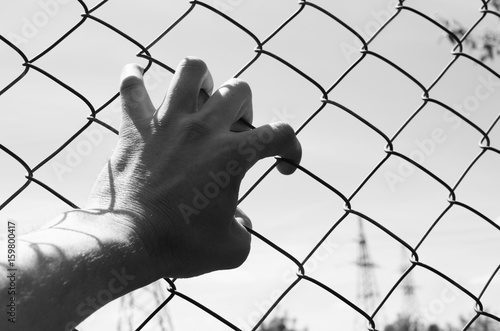 Refugee hand on fence. Refugee concept.Dark tone. Vintage.