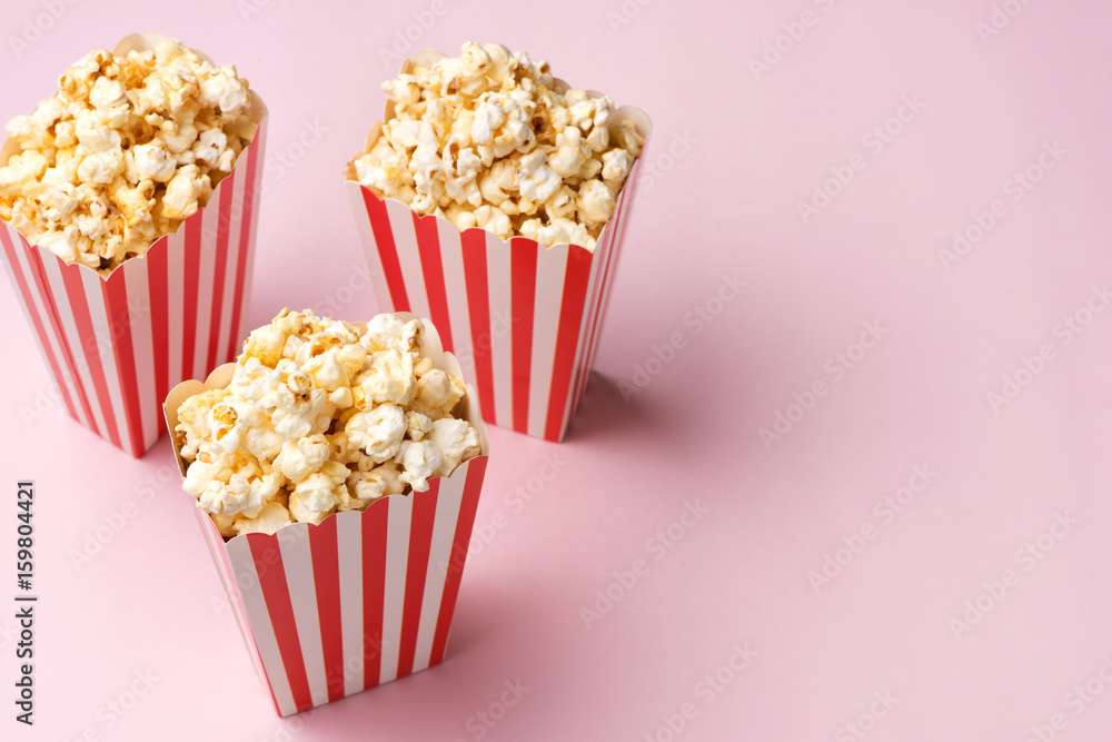 Popcorn in red and white cardboard box on the pink background.