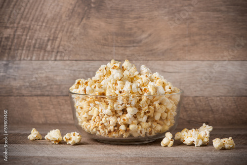 Popcorn in a bowl on the wooden table.