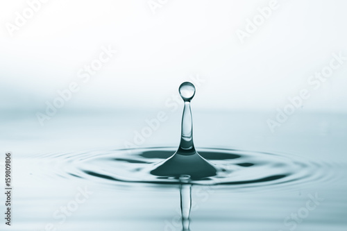 Water drop and splash on water surface on blue background