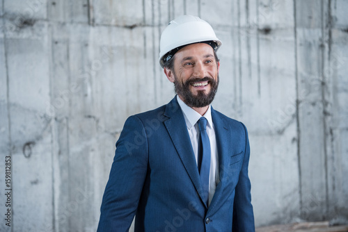 Professional middle aged architect in helmet smiling and looking away © LIGHTFIELD STUDIOS
