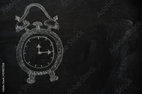 School alarm clock drawn with chalk on blackboard and copyspace photo