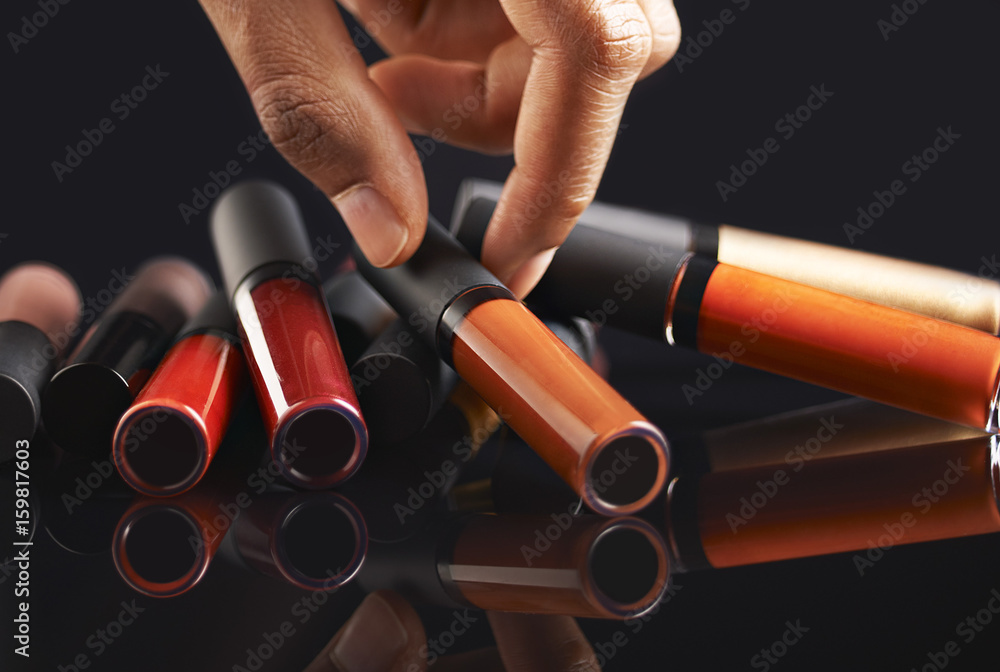 Fototapeta premium Hand holding a liquid lipstick on black background