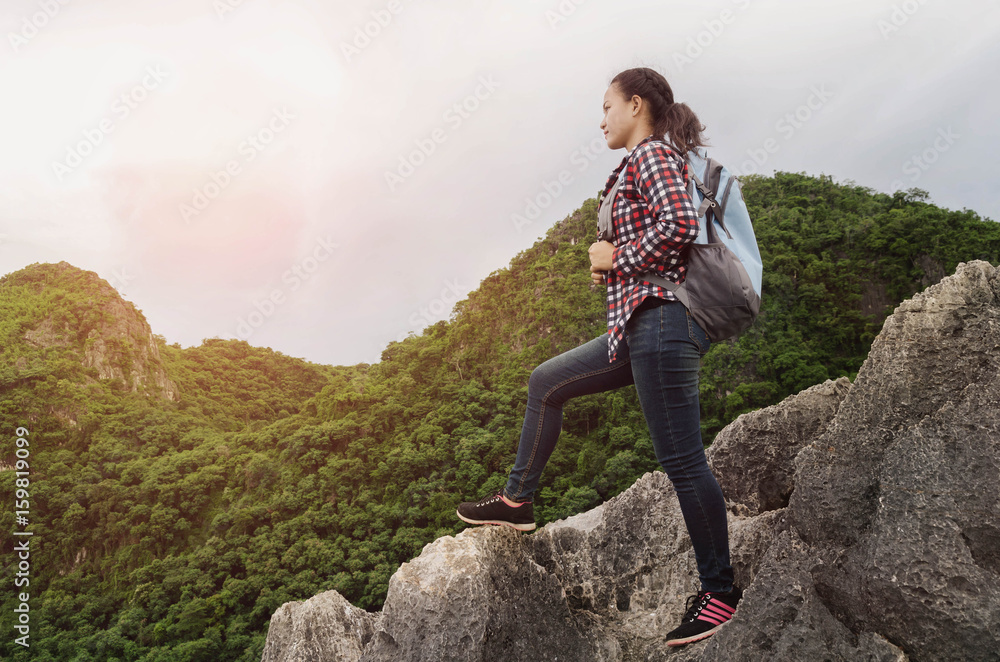 Happy beautiful woman traveler with backpack standing on top of a mountain and enjoying sunset view of thailand Happy beautiful woman traveler with backpack standing on top of a mountain and enjoying sunset view of thailand
