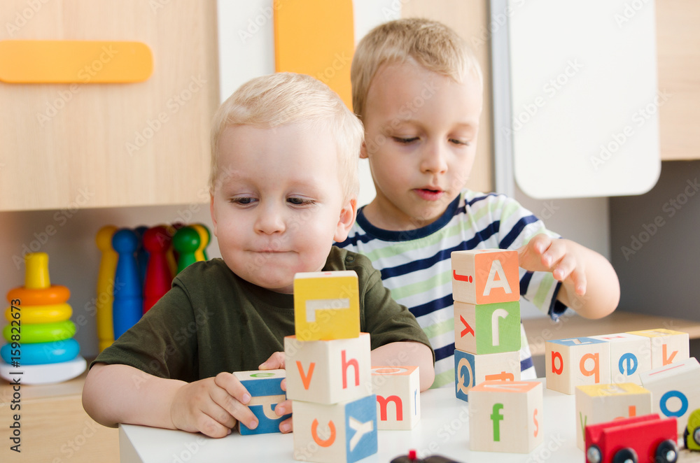 Kids boys playing with toy blocks at home or kindergarten Kids boys playing with toy blocks at home or kindergarten