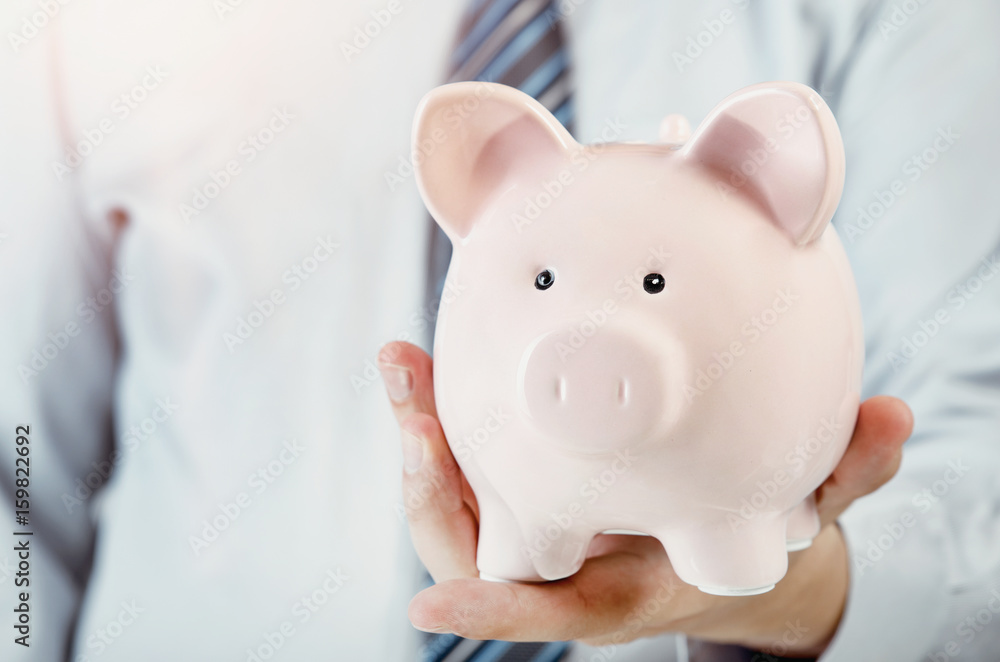 Business man holding piggy bank in hand Business man holding piggy bank in hand