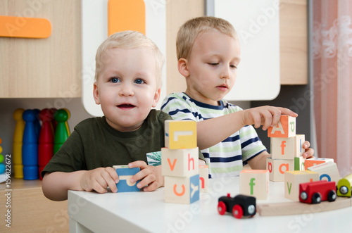 Kids boys playing with toy blocks at home or kindergarten