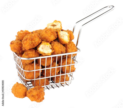 Fotografie Fried breadcrumb covered chicken popcorn in a small wire frying basket isolated