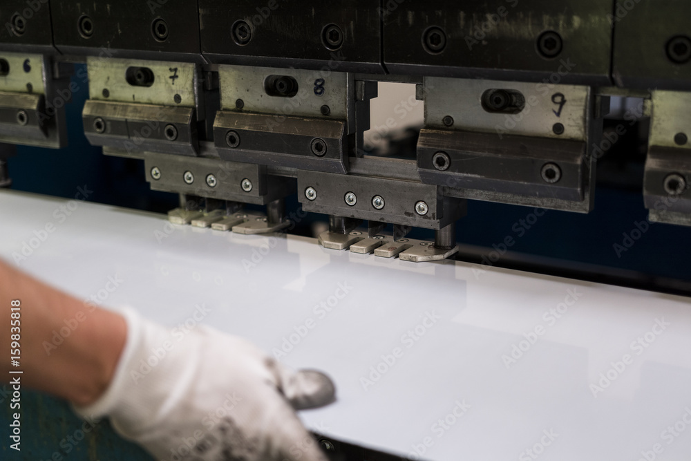 Worker bending a sheet of aluminium.