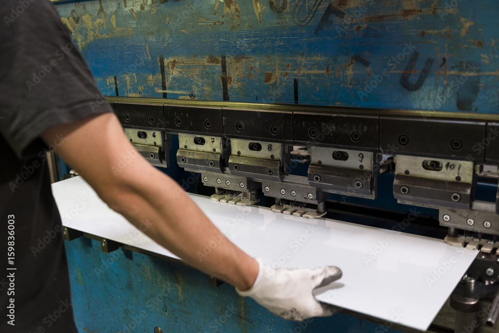Worker bending a sheet of aluminium. - obrazy, fototapety, plakaty 