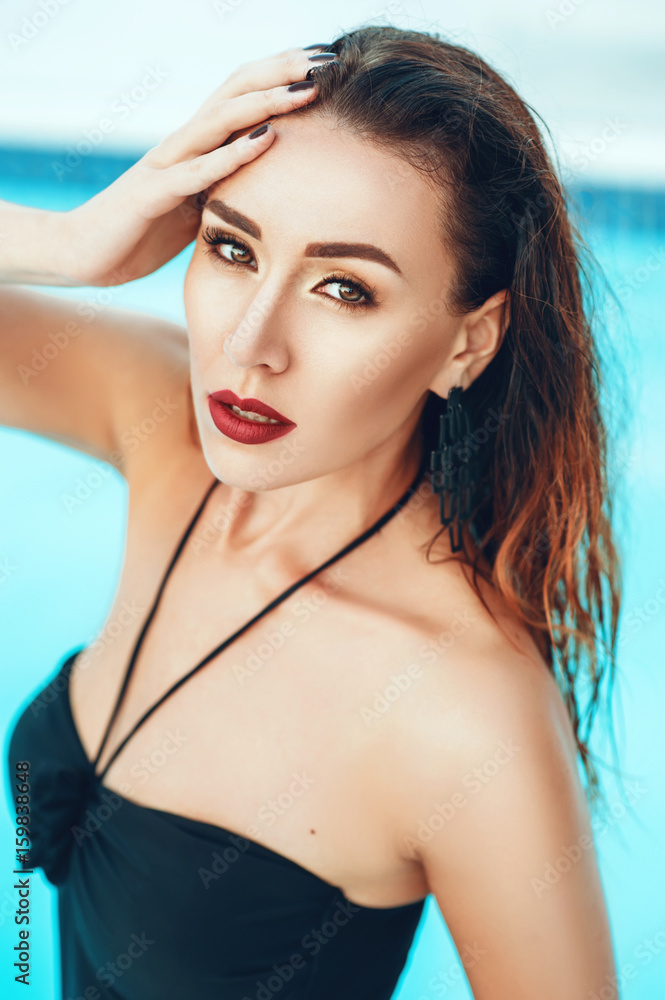 Close up portrait of Elegant sexy woman in black bikini on beautiful body is posing near the swimming pool in private villa. Sexuality beauty. Hot weather outside time to have rest and swim in pool.