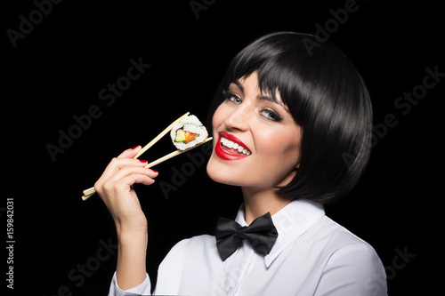 Woman in texedo holding suschi by chopsticks isolated