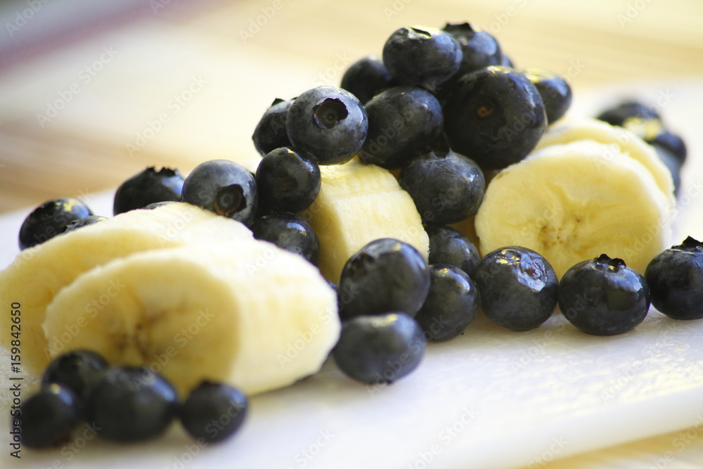 Bananas in slices and blueberries on a white board Bananas in slices and blueberries on a white board