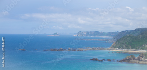 Amazing landscape with ocean, cliffs, beach, greens and flowers in summer day; wallpaper of the Bay of Biscay, Cantabrian Sea
