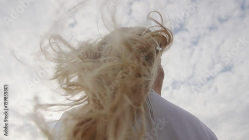 Blonde hair with curls shaking behind her back during gait of a young woman. Beautiful, well maintained, painted, stacked hair long hair.