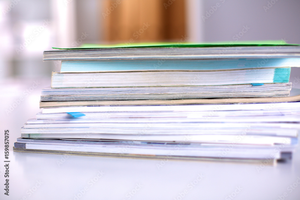 A stack of documentation is on the desktop in the office A stack of documentation is on the desktop in the office