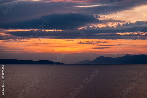 Horizontal image of deep coloured sunset with blue  purple and golden hues  black mountains on the horizon 