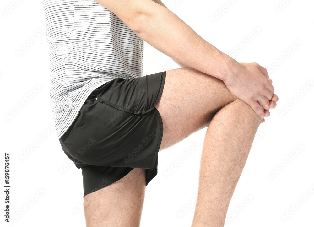Young man suffering from pain in leg on white background