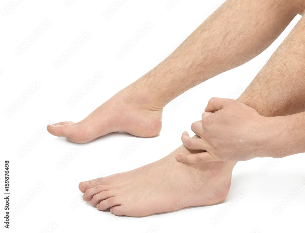 Young man suffering from pain in leg on white background, closeup Young man suffering from pain in leg on white background, closeup