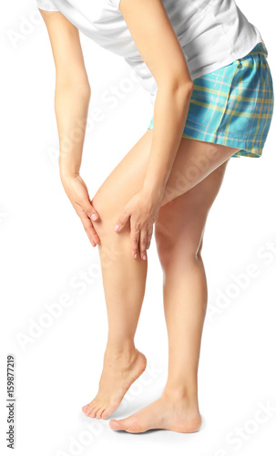 Young woman suffering from pain in leg on white background