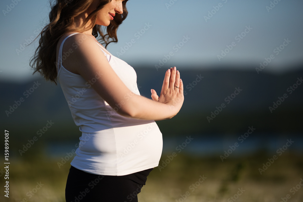 Beautiful pregnant woman doing sports in the camomile field Beautiful pregnant woman doing sports in the camomile field