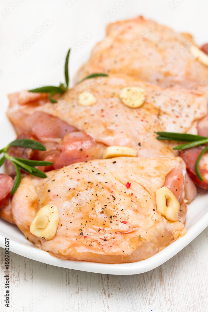 raw marinated chicken with smoked sausage on white dish raw marinated chicken with smoked sausage on white dish