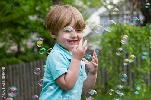 adorable toddler boy playing with bubbles outside in springtime 
