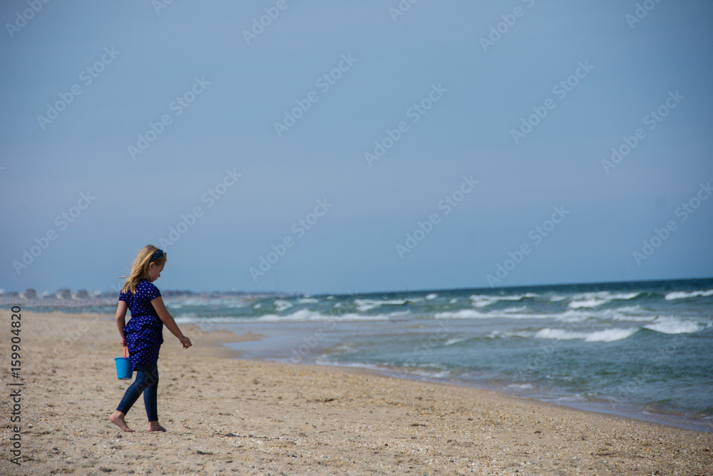 adorable school age girl playing on sandy beach